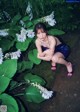 A woman in a blue dress sitting on the ground next to some flowers.