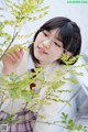 A young woman wearing glasses standing next to a tree.