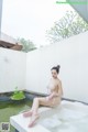 A woman sitting in a bathtub with foam on her feet.