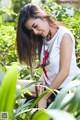 A woman in a white shirt is sitting in the grass.