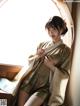 A woman in a kimono sitting on a window sill.