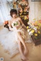 A woman in a wedding dress sitting on the floor with flowers.