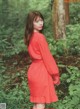 A woman in a red dress standing in the woods.