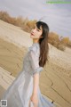 A woman in a white dress standing in the desert.