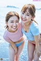 Two young women standing next to each other on a beach.