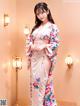 A woman in a pink kimono standing in a room.