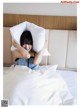 A woman laying in bed with a pillow on her head.