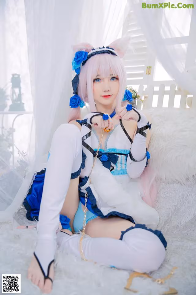 A woman in a blue and white outfit sitting on a white rug.
